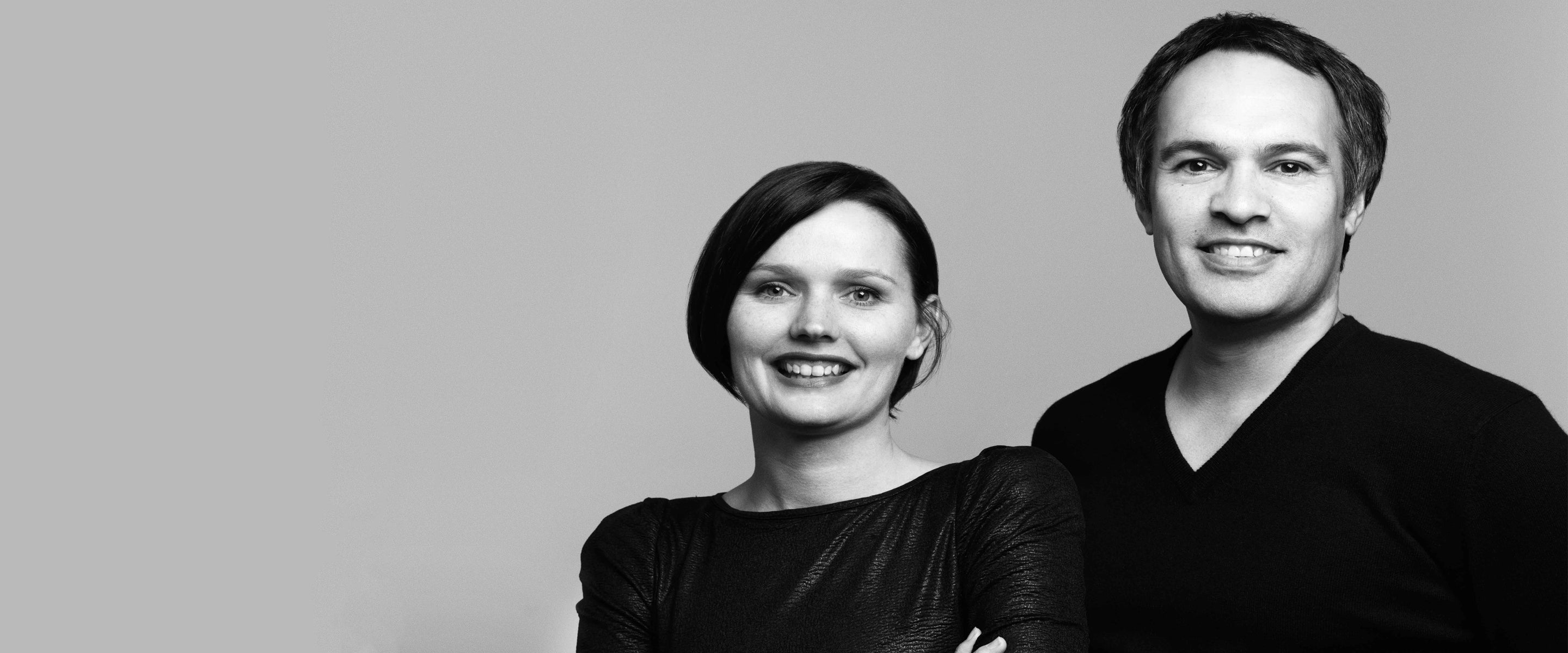 Black and white portrait of aCarl and Belinda Keeley standing side by side against a plain background