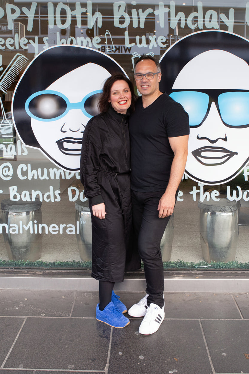 Carl and Belinda standing in front of the Chumba window with large sunglasses and faces on the glass.